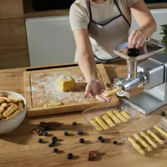 Przygotowywanie kruche ciasteczka do długiego przechowywania. Maszyna do ciastek formuje paski ciasta, które trafiają do pojemników.