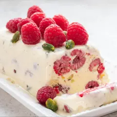 Pyszne lody z ciasta z malinami i pistacjami, ozdobione świeżymi owocami. Idealny deser na gorące dni.