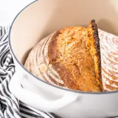 Złocisty bochenek chleba, właśnie wyjęty z garnka, pokazuje, jak się piecze chleb. Skórka jest chrupiąca, a wnętrze pachnące.