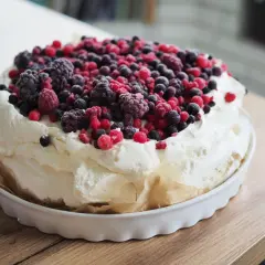 Beza pavlova z 10 białek, obficie udekorowana mrożonymi owocami leśnymi. Puszysta masa i kolorowe owoce tworzą apetyczny deser.
