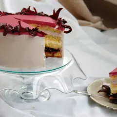 Różowy tort z kremem hibiskusowym, ozdobiony suszonymi kwiatami hibiskusa.