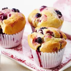 Puszyste muffinki z borówką amerykańską, z widocznymi owocami i sokiem wypływającym z ciasta.