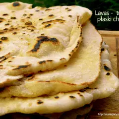 Stos puszystego, lekko przypieczonego **chleba tureckiego** na drewnianej desce. Idealny do dipów i jako dodatek do dań.