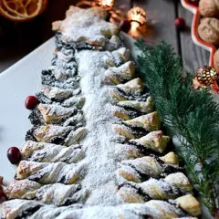 Pyszna choinka makowa, udekorowana cukrem pudrem i żurawiną, wygląda jak świąteczny przysmak.