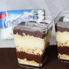 Deser w pucharkach z warstwami czekolady, ciastek i kremu z mleka w proszku.