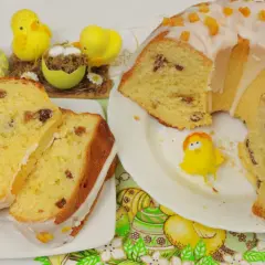 Pyszna babka drożdżowa z rodzynkami, ozdobiona lukrem i kandyzowaną skórką pomarańczową, w towarzystwie wielkanocnych kurczaczków.