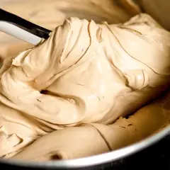 Gładka, kremowa masa o kolorze **salted caramel** jest mieszana łopatką w metalowej misce.