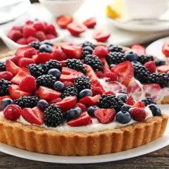 Pyszna tarta z kremem patissiere, obficie udekorowana świeżymi malinami, borówkami, jeżynami i truskawkami.