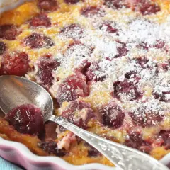 Pyszne clafoutis z wiśniami, posypane cukrem pudrem, czeka na łyżeczkę. Idealny deser na letnie popołudnie.