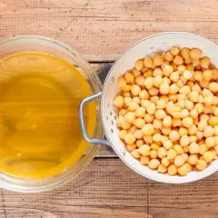 Ciecierzyca w durszlaku i aquafaba w misce, składniki na wegańską bezę z ciecierzycy.