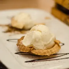 Dwa gałki lodów waniliowych w wafelku, ozdobione czekoladą. Idealne, nowoczesne desery.