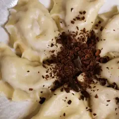 Urocze pierogi z czekoladą, posypane wiórkami gorzkiej czekolady, tworzą apetyczny deser.
