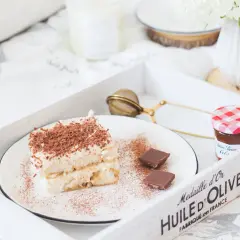 Pyszne tiramisu z biszkoptami, posypane kakao i czekoladą, na tacy z dżemem i kwiatami. Idealne na leniwe popołudnie.