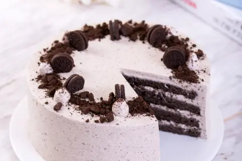 Pyszny krem oreo z czym łączyć? Z ciastem czekoladowym i bitą śmietaną, udekorowany pokruszonymi ciasteczkami.