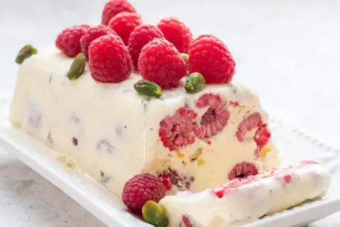 Pyszne lody z ciasta z malinami i pistacjami, ozdobione świeżymi owocami. Idealny deser na gorące dni.