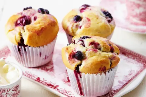 Puszyste muffinki z borówką amerykańską, z widocznymi owocami i sokiem wypływającym z ciasta.