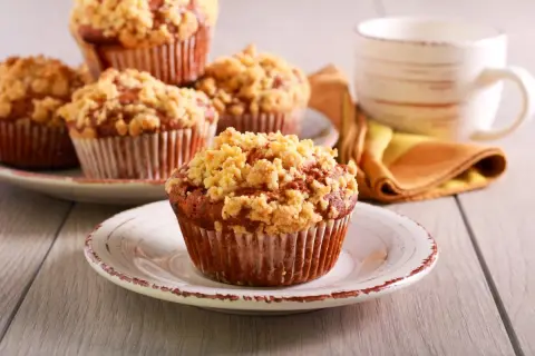 Pyszne muffinki drożdżowe z kruszonką na talerzykach, obok filiżanka kawy.