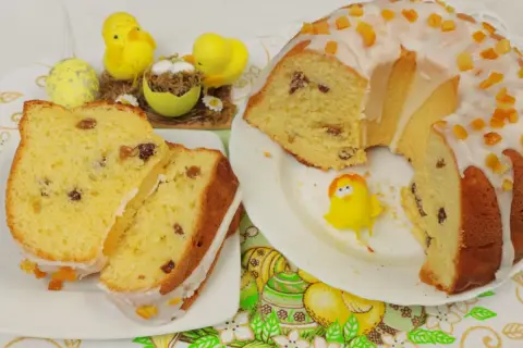Pyszna babka drożdżowa z rodzynkami, ozdobiona lukrem i kandyzowaną skórką pomarańczową, w towarzystwie wielkanocnych kurczaczków.