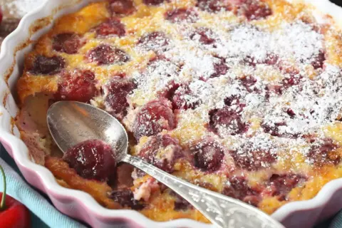 Pyszne clafoutis z wiśniami, posypane cukrem pudrem, czeka na łyżeczkę. Idealny deser na letnie popołudnie.