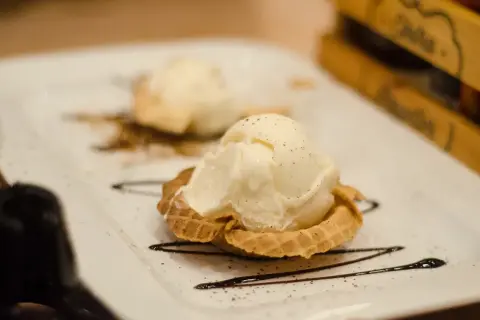 Dwa gałki lodów waniliowych w wafelku, ozdobione czekoladą. Idealne, nowoczesne desery.