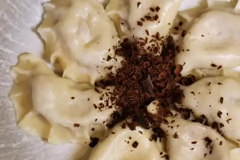 Urocze pierogi z czekoladą, posypane wiórkami gorzkiej czekolady, tworzą apetyczny deser.