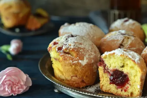 Puszyste muffinki z dżemem, posypane cukrem pudrem, kuszą swoim domowym wyglądem.