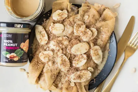 Naleśniki z bananami i czekoladową posypką, polane obficie kremową polewą z masła orzechowego.