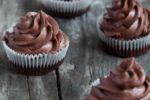 Kilka pysznych muffinek z kremem czekoladowym, ułożonych na drewnianym blacie.