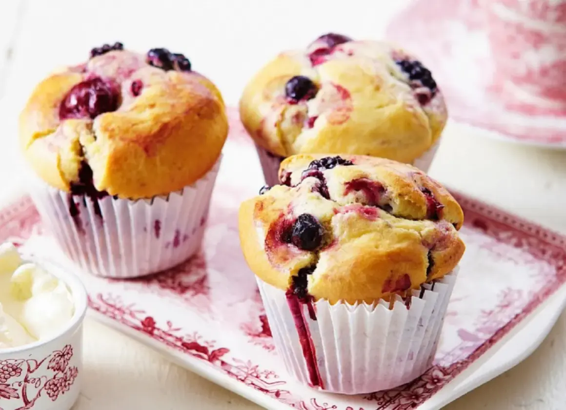 Puszyste muffinki z borówką amerykańską, z widocznymi owocami i sokiem wypływającym z ciasta.