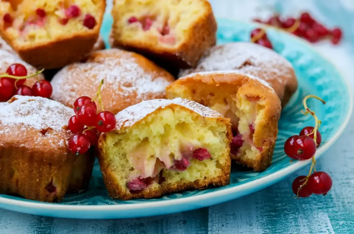 Puszyste muffinki z czerwoną porzeczką, posypane cukrem pudrem, kuszą swoim wyglądem. Idealne na letnie popołudnie.