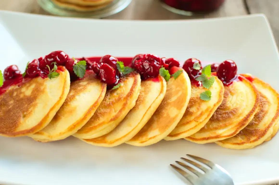 Puszyste pancakes na maślance, polane wiśniowym sosem i ozdobione listkami mięty. Idealne na słodkie śniadanie.