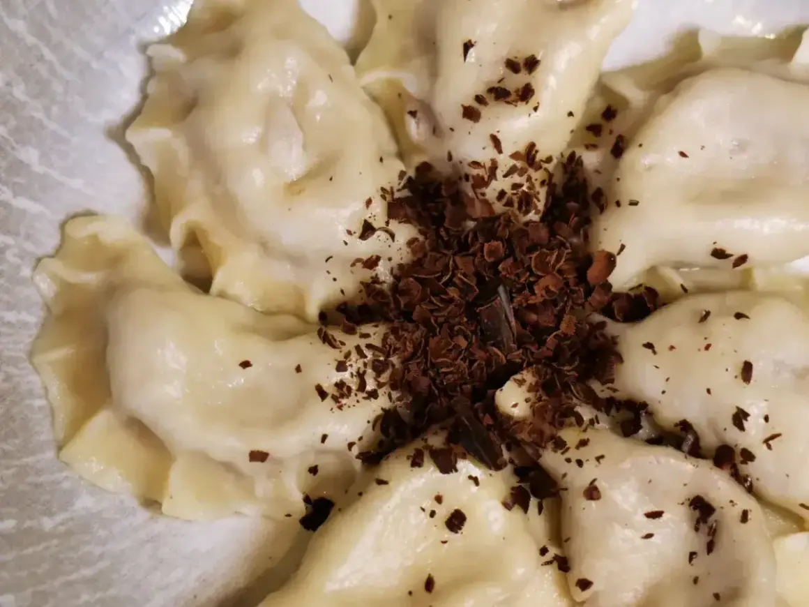 Urocze pierogi z czekoladą, posypane wiórkami gorzkiej czekolady, tworzą apetyczny deser.