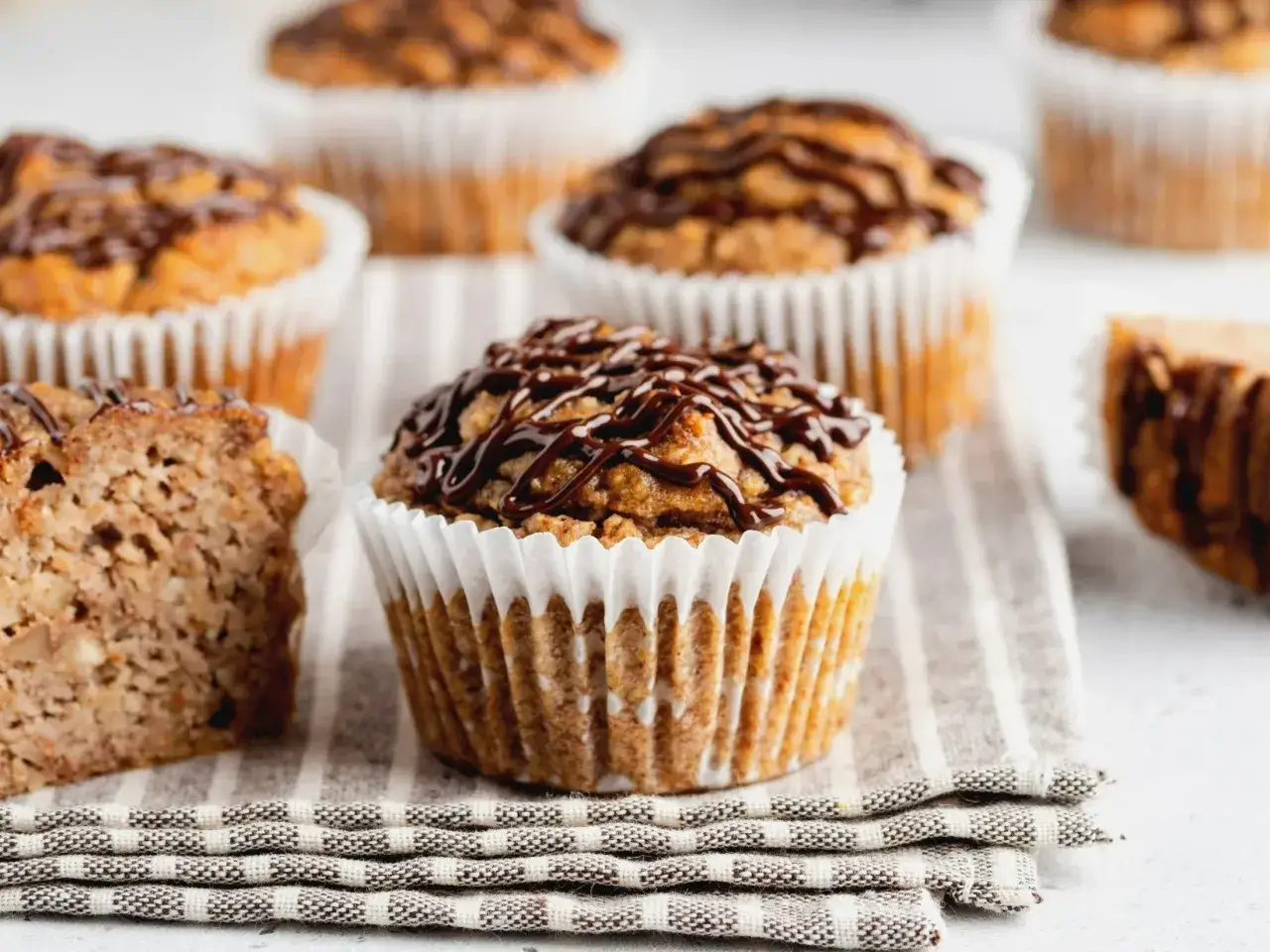 Pyszne muffinki bananowe z polewą czekoladową, jedna przekrojona, ukazująca wilgotne wnętrze.