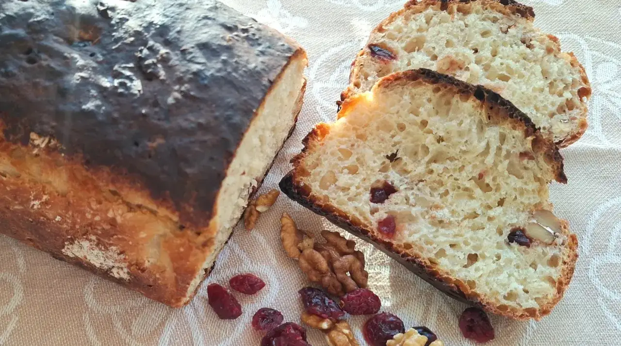 Chleb z żurawiną i orzechami włoskimi, pokrojony w kromki, prezentuje się apetycznie.