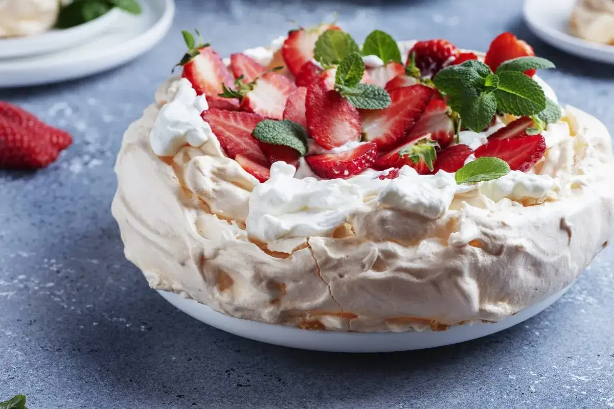 Puszysta beza z mascarpone, udekorowana świeżymi truskawkami i miętą, kusi swoim wyglądem.