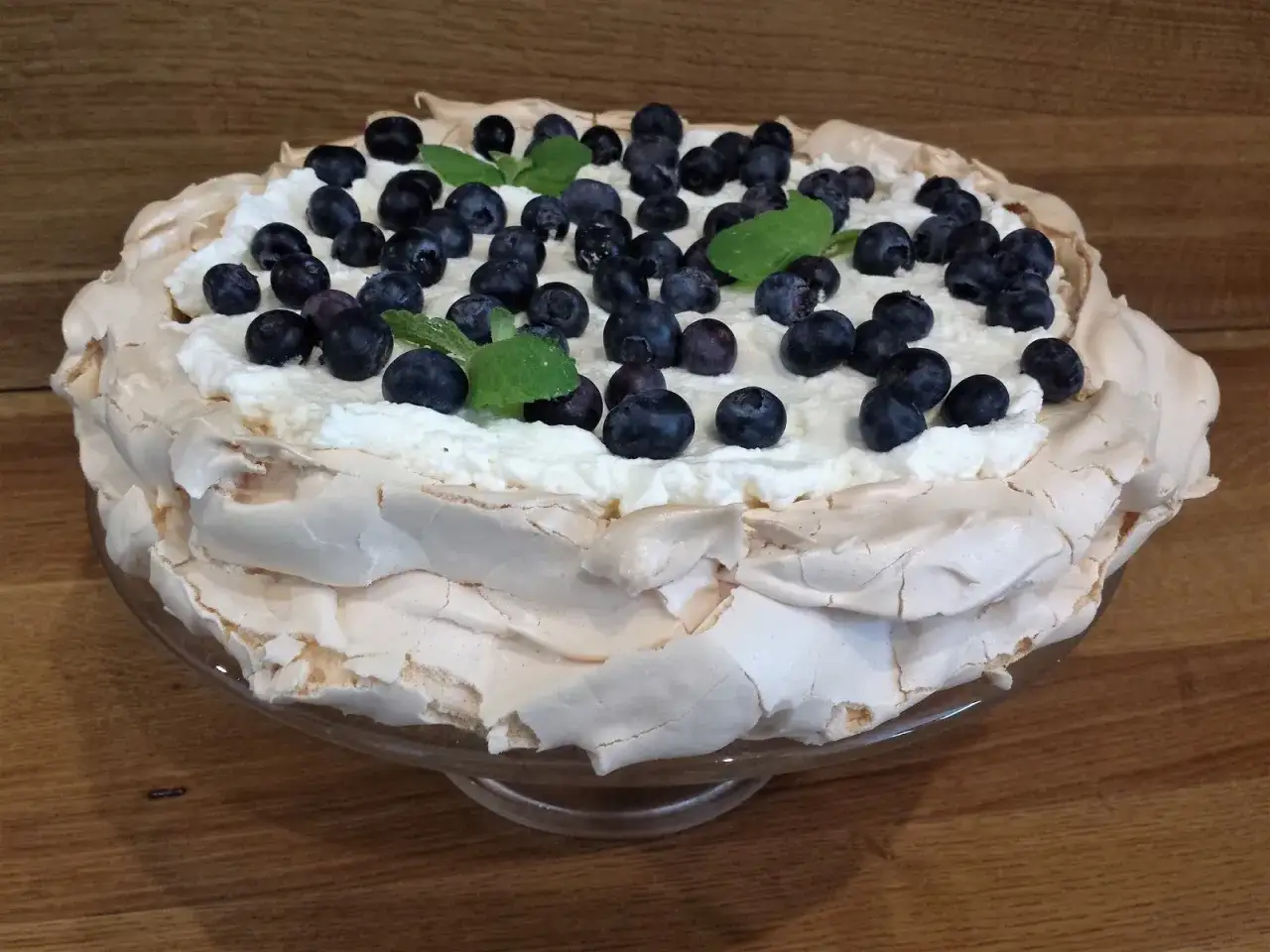 Pyszny tort bezowy z bitą śmietaną i borówkami. Czy tort bezowy można zrobić dzień wcześniej? Tak, ten wygląda idealnie!