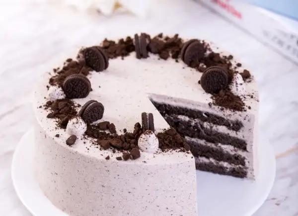 Pyszny krem oreo z czym łączyć? Z ciastem czekoladowym i bitą śmietaną, udekorowany pokruszonymi ciasteczkami.