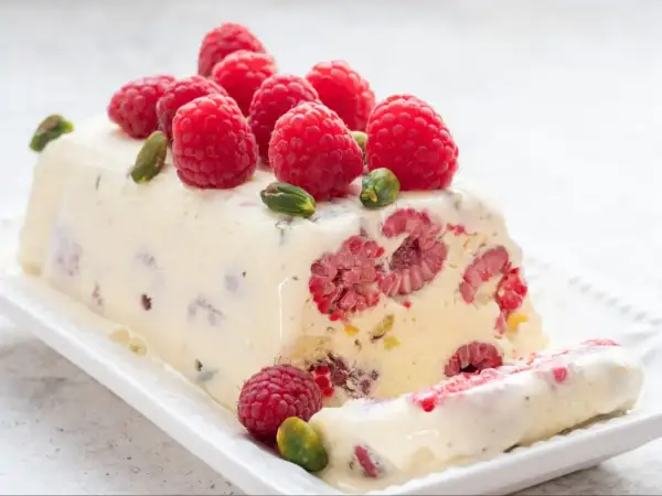 Pyszne lody z ciasta z malinami i pistacjami, ozdobione świeżymi owocami. Idealny deser na gorące dni.