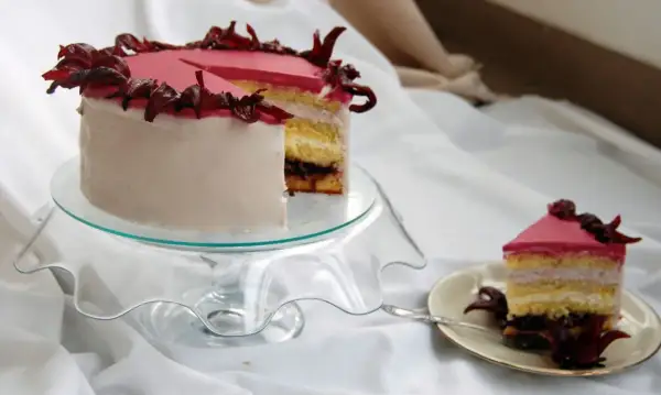 Różowy tort z kremem hibiskusowym, ozdobiony suszonymi kwiatami hibiskusa.