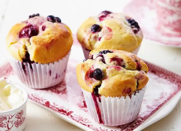 Puszyste muffinki z borówką amerykańską, z widocznymi owocami i sokiem wypływającym z ciasta.