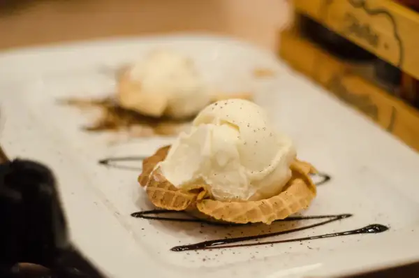 Dwa gałki lodów waniliowych w wafelku, ozdobione czekoladą. Idealne, nowoczesne desery.