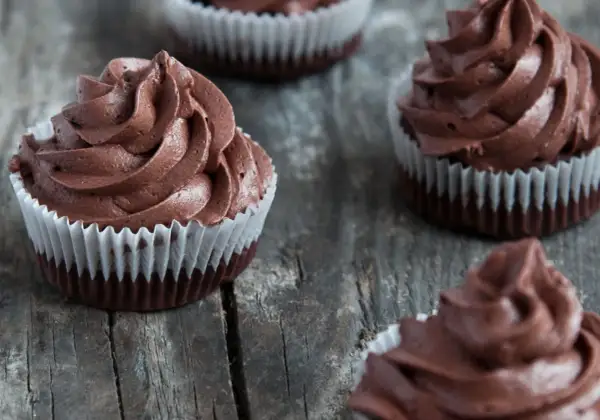 Kilka pysznych muffinek z kremem czekoladowym, ułożonych na drewnianym blacie.